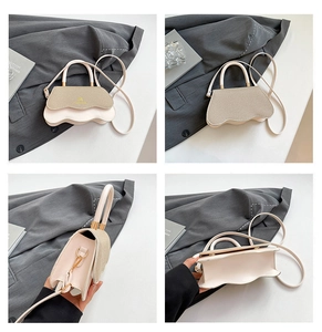Detail view of stylish color-block handbag featuring wavy flap and golden logo accents