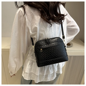 Detail of black woven crossbody shell bag featuring gold zippers and premium PU leather