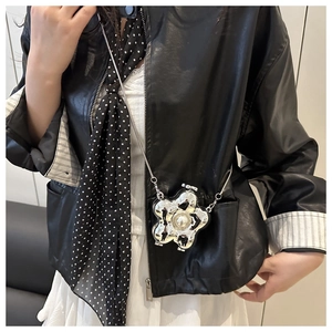 Silberne Blumen-Umhängetasche mit Perle und Metallkette auf einem Lederjacken-Outfit