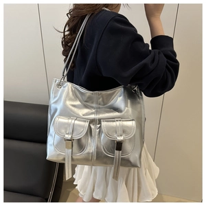 Detailed view of silver metallic shoulder bag with front buckle pockets and slim straps