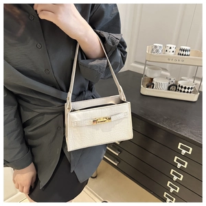 Detail view of white crocodile pattern shoulder bag with golden twist lock on model