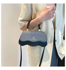 Detail of a chic color-block handbag with denim flap and unique wavy base design