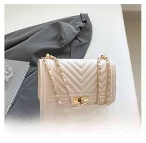 Detail of V-quilted beige small square bag with golden chain strap and turn-lock closure