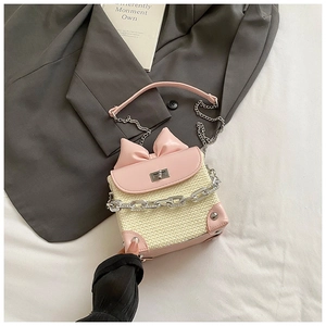Detail of pink leather and woven straw crossbody bag with bow and silver chain strap