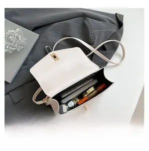 Detalle de la capacidad interna del bolso bandolera de cuero blanco con objetos diarios