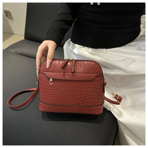 Detailed view of red shell-shaped crossbody bag with woven texture and gold hardware
