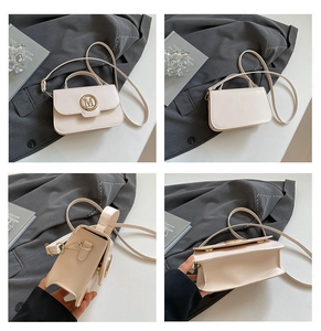 Detail of cream leather crossbody bag with golden M metal buckle and accordion pleats