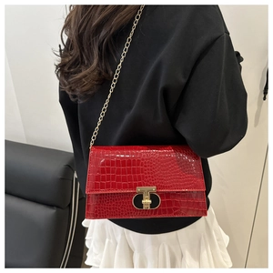 Close-up of red crocodile pattern handbag with gold T-shaped clasp and chain detail