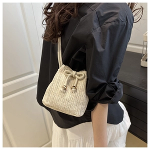 Detail of beige hand-woven bucket bag with drawstring closure and fine V-shaped straw texture