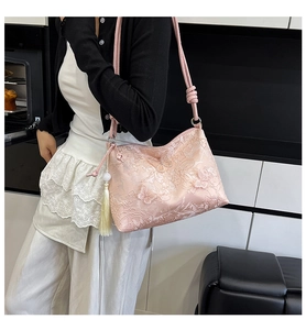 Détail du sac à bandoulière rose brodé avec papillons 3D et pompon jaune décoratif