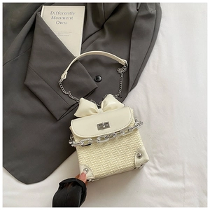 Detailed view of cream-white woven bag with bow ornament and silver twist lock