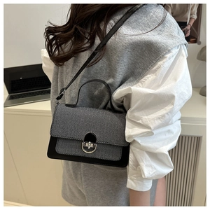 Detail of a two-tone crossbody bag with grey tweed flap and black leather handle