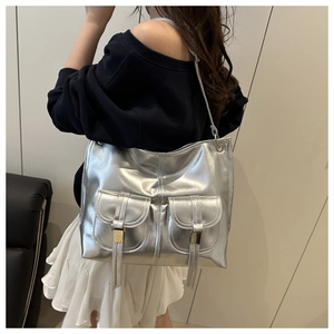 Detailed view of silver metallic tote bag with buckle pockets on model for casual wear