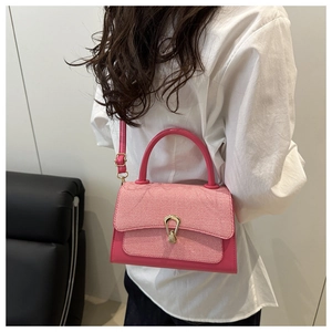 Detail of pink contrast flap bag with metal U-buckle worn by model for daily commute