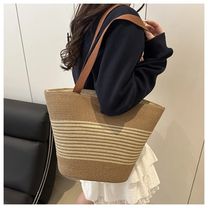 Detail of a brown and beige striped woven cotton rope tote bag shown on a shoulder