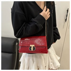Close-up of red crocodile pattern shoulder bag with a gold T-bar buckle and chain strap