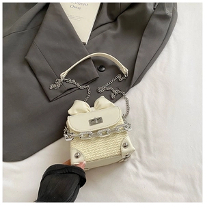Detail of cream mini crossbody bag with woven texture, bow accent and silver chain
