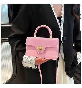 Detail of pink satchel showing the braided handle and golden flower-shaped metal clasp