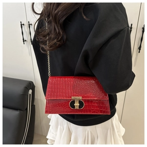 Close-up of glossy red crocodile texture bag featuring elegant gold T-shaped metal clasp