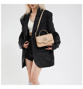 Detailed close-up of apricot leather handbag featuring a gold M letter metal buckle