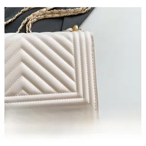 Close-up of quilted V-pattern stitching on white soft leather bag with gold chain strap