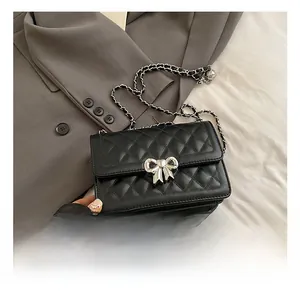 Vue détaillée du sac en cuir noir matelassé avec boucle nœud argentée sur un costume