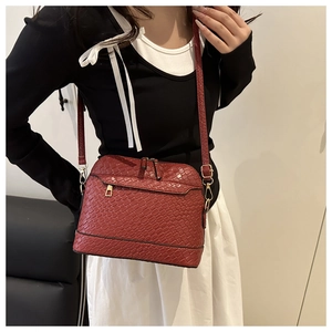 Détail du sac bandoulière rouge texture crocodile avec ferrures en métal doré