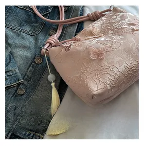 Détail macro d'un sac en dentelle rose avec broderies de fleurs 3D et papillons ornés