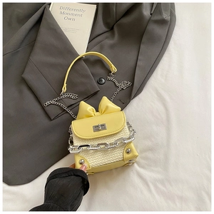 Detail of yellow woven crossbody bag with a 3D bow and stylish chunky metal chain
