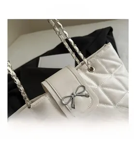 Close-up of white quilted leather texture with silver metal bow clasp and chain strap