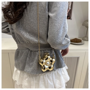 Nahaufnahme der goldenen Blumen-Acryltasche mit Perle und eleganter feiner Kette