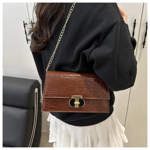 Close-up of brown crocodile pattern shoulder bag with gold chain and metal lock