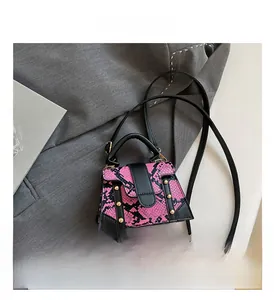 Close-up of pink snakeskin mini bag with golden rivets on a grey suit jacket background