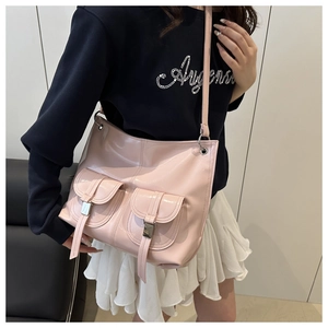 Pink glossy shoulder bag with twin front pockets worn by a model in casual outfit