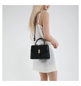 Elegante bolso de mano en cuero negro con cierre de giro dorado en una foto de estudio