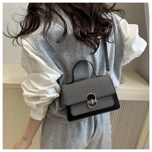 Detailed view of silver oval metal twist lock on black leather and tweed crossbody bag