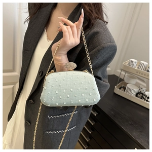 Detail of mint green clutch bag with tufted texture and sparkling rhinestone clasp decoration