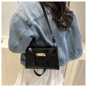 Detail of black crocodile pattern PU handbag with elegant gold metal lock and shoulder strap