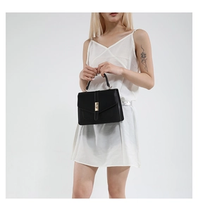 Detalle del bolso bandolera de cuero negro con elegante cierre metálico dorado de lujo