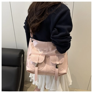 Detail of light pink patent leather tote bag featuring two front pockets and metal buckles