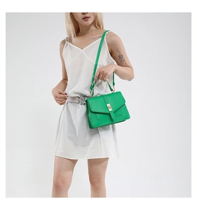 Detalle de bolso de cuero verde vibrante con hebilla dorada y correa de hombro