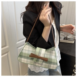 Detail of green and white plaid baguette bag with a brown bow on female model