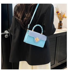 Light blue crossbody bag featuring a floral metal clasp and woven handle on a model