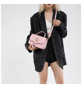 Detail of pink crossbody bag with a golden M logo buckle shown on a model