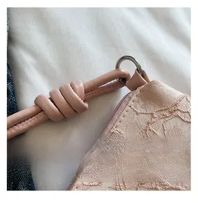 Vue macro de la texture jacquard rose et bandoulière nouée avec anneaux métalliques