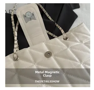 Detail of magnetic snap closure and leather chain strap on white quilted handbag