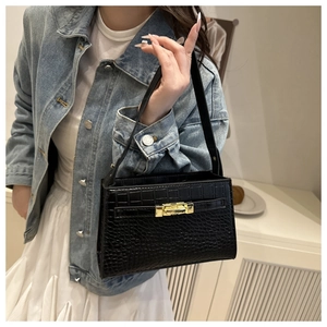 Detail of black crocodile pattern PU leather bag with golden metal lock and fine texture