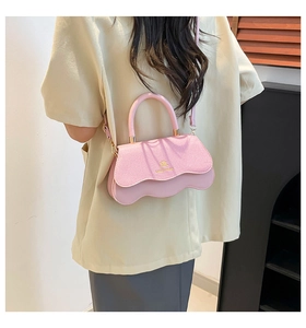 Close-up of light pink handbag featuring scalloped flap edge and gold metallic logo