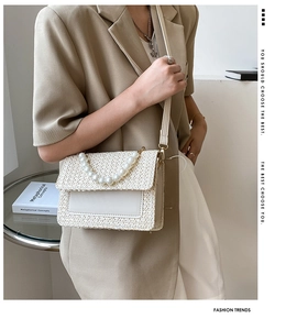 Detailed view of cream woven crossbody bag featuring a large pearl handle and strap