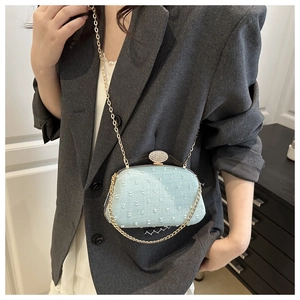 Detailed view of light blue textured crossbody bag with rhinestone buckle and gold chain